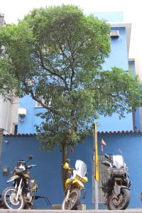 two motorcycles parked next to a tree and a blue wall at Copacabana Hostel in Rio de Janeiro