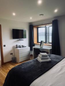 1 dormitorio con 1 cama, escritorio y TV en An Taigh Mòr, en Eriskay