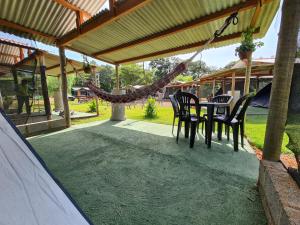 een patio met stoelen, een tafel en een hangmat bij Camping Valle das Aguas in Socorro
