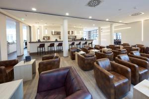 a waiting room with leather chairs and a bar at GHOTEL hotel & living Göttingen in Göttingen