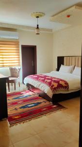 Petra Stones Inn في وادي موسى: غرفة نوم بسرير كبير وسجادة