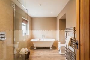 a bathroom with a tub and a toilet at The Percy Arms in Chatton +10 photos