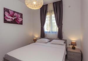 a bedroom with a white bed and a window at Engora 5 in Petrovac na Moru