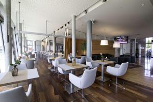 un restaurante con mesas blancas y sillas blancas en Nordsee Hotel Fischereihafen, en Bremerhaven