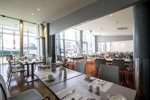 a restaurant with tables and chairs and windows at Nordsee Hotel Fischereihafen in Bremerhaven