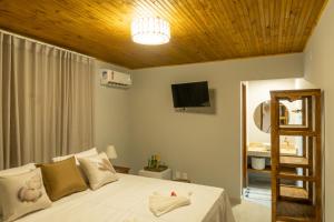 a bedroom with a white bed with a wooden ceiling at Tropical Beach in Porto Seguro