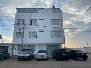 un grupo de autos estacionados en un estacionamiento frente a un edificio en Hotel Munay, en Paracas