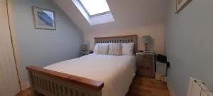 a bedroom with a large white bed with a skylight at Blacksmiths in Dartmouth