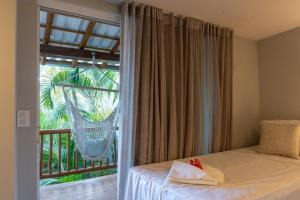 a bedroom with a bed and a balcony with a hammock at Tropical Beach in Porto Seguro