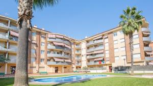 ein Apartmentgebäude mit einem Pool und einer Palme in der Unterkunft 2 Ross - Lloret de Mar in Lloret de Mar