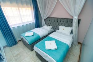 dwa łóżka w pokoju niebiesko-białym w obiekcie Villa Karibu Serviced Apartments-Kampala w mieście Kampala