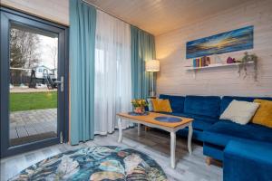 a living room with a blue couch and a table at Domki letniskowe Alma, Jarosławiec in Jarosławiec +13 photos