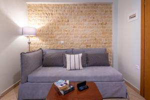 Sea Breeze Hotel & Apartments في آغيوس غوذيوس: أريكة في غرفة معيشة مع جدار من الطوب