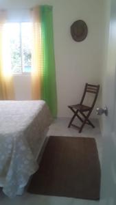 
a bedroom with a bed, chair, lamp and window at Punta Cana Macao Guest House in Salado
