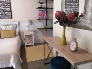 a bedroom with a bed and a table with a vase of flowers at Shai's Studio in Centurion