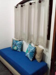 a bed with blue pillows and a window with a curtain at Excellence Apart in Ubatuba