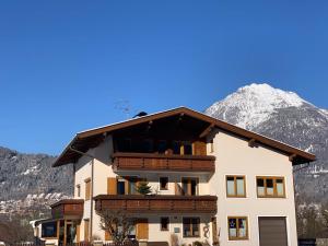 un immeuble d'appartements avec une montagne en arrière-plan dans l'établissement Gästehaus Hechenblaikner, à Maurach