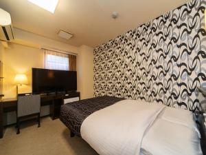 sypialnia z łóżkiem, biurkiem i telewizorem w obiekcie APA Hotel Osaka-Kadomashi Ekimae w Osace