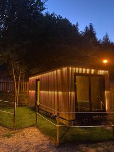 a building with a fence and a tree at night at Pichoses Gerês Camping in Rio Caldo