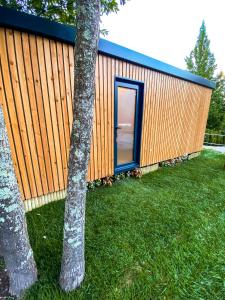ein kleines Holzgebäude mit einer blauen Tür neben einem Baum in der Unterkunft Pichoses Gerês Camping in Rio Caldo