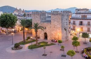 an old stone building with palm trees in a courtyard at Sea Lovers Apartment in Alcudia