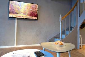 a living room with a tv hanging on a wall at Splendide Maison 5 chambres ! Quartier Historique in Limoges