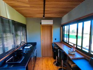 a kitchen with a sink and a counter with windows at Tinyhouse da Floresta in Urubici