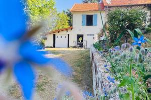 un jardin avec des fleurs bleues devant une maison dans l'établissement La Belle Vue - Coin de paradis, à Sussac