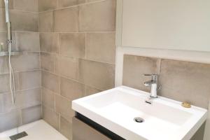 La salle de bains est pourvue d'un lavabo blanc et d'une douche. dans l'établissement Lovely T2 - Proche du CHU LIMOGES, à Isle