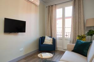 a living room with a tv and a blue chair at Casa Cosi - El Farro 2 in Barcelona