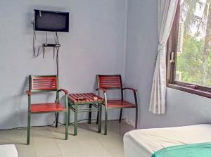 2 sillas y TV en una habitación en Wisma Tulus Syariah Kebumen Mitra RedDoorz, en Kebumen