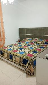 a bed with a quilt on it in a room at Maison koukou in Boumhel El Bassatine