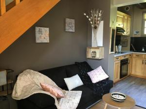a living room with a black couch and a kitchen at gîte le couraduque avec bain nordique et sauna en pleine montagne in Arrens-Marsous