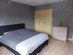 een slaapkamer met een groot bed en een houten kast bij Aux trois petits cochons in Hotton