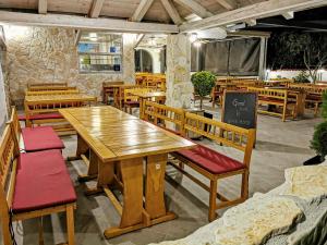 a restaurant with wooden tables and benches and a chalkboard at Pansion Karoca in Vodice
