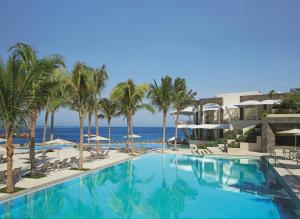 a swimming pool with palm trees and the ocean at Secrets Vallarta Bay Resort & SPA - Adults Only in Puerto Vallarta