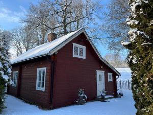 ein kleines rotes Haus mit Schnee auf dem Dach in der Unterkunft Naturskönt boende nära Skövde in Skövde