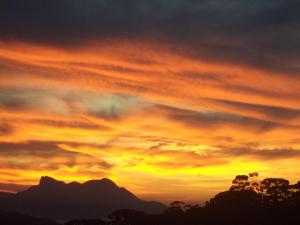 un coucher de soleil dans le ciel et des montagnes en arrière-plan dans l'établissement Casa do Índio, à Visconde de Mauá