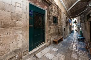 an alley with a green door and a bench at Nautica Room 1 - Old Town in Dubrovnik