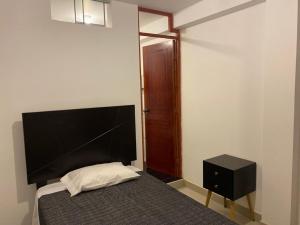 ein Schlafzimmer mit einem Bett und einem schwarzen Nachttisch in der Unterkunft Hotel Munay in Paracas