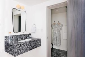 a bathroom with a black and white sink and a mirror at Short Stories Hotel in Los Angeles