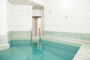 a bathroom with a swimming pool with blue tiles at Hotel Akvamarin in Leninogorsk