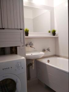 a white bathroom with a sink and a washing machine at Noclegi - ul Śliczna in Wrocław