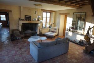 ein Wohnzimmer mit einem Sofa, einem Tisch und einem Kamin in der Unterkunft une oasis dans le perche in Rémalard