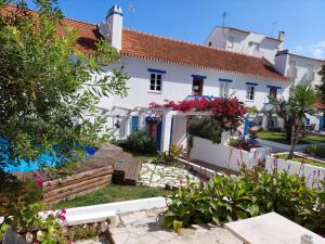 une maison blanche avec des fleurs devant elle dans l'établissement Olive3 Ericeira, à Ericeira