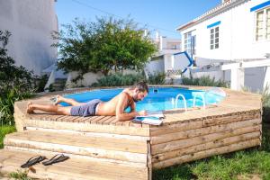 a man laying on a deck next to a swimming pool at Olive3 Ericeira in Ericeira