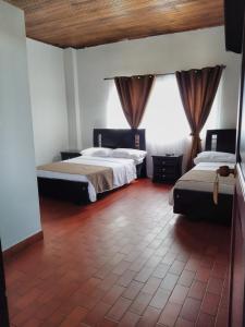 1 dormitorio con 2 camas y suelo de baldosa roja en HOTEL MORGAN, en Guaduas