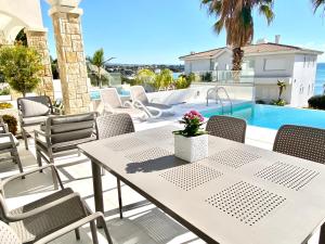 eine Terrasse mit Tisch und Stühlen und ein Swimmingpool in der Unterkunft coral bay beach villa in Paphos City
