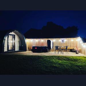 The Stag Pod Farm Stay with Hot Tub Sleeps 2 Ayrshire Rural Retreats في Galston: مبنى به طاولة وكراسي في ساحة في الليل