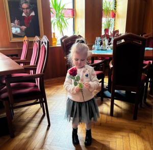 a little girl holding a flower in a restaurant at Hotel Zur Sonne in Falkenstein